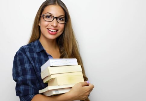 Happy beautiful student girl with eyeglasses and stack of books
