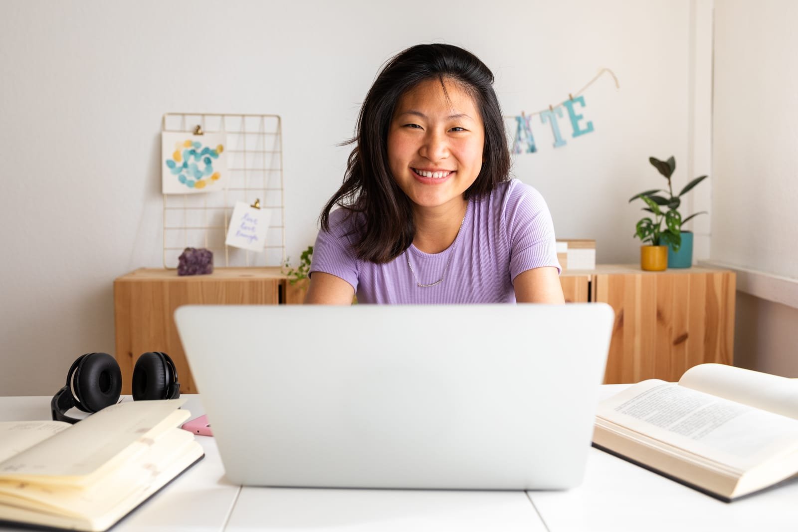51720962_happy-smiling-teen-asian-female-college-student-studying-at-home-doing-homework-using-laptop-looking-at-camera
