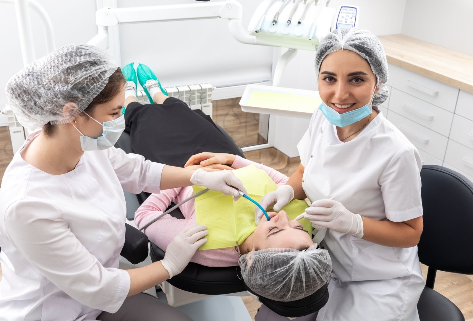49242700_dentist-and-assistant-performing-dental-treatment-inmodern-dental-clinic-patient-laying-in-a-chair