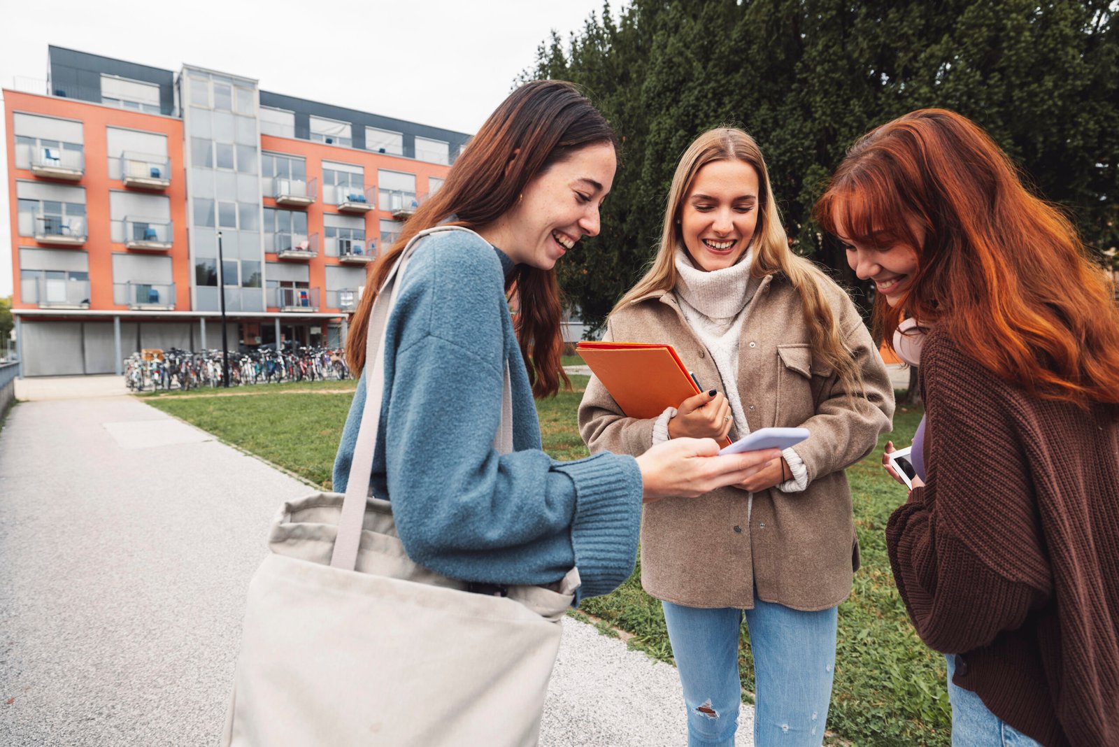 Best friends on college laughing about something while standing outside on the campus grounds
