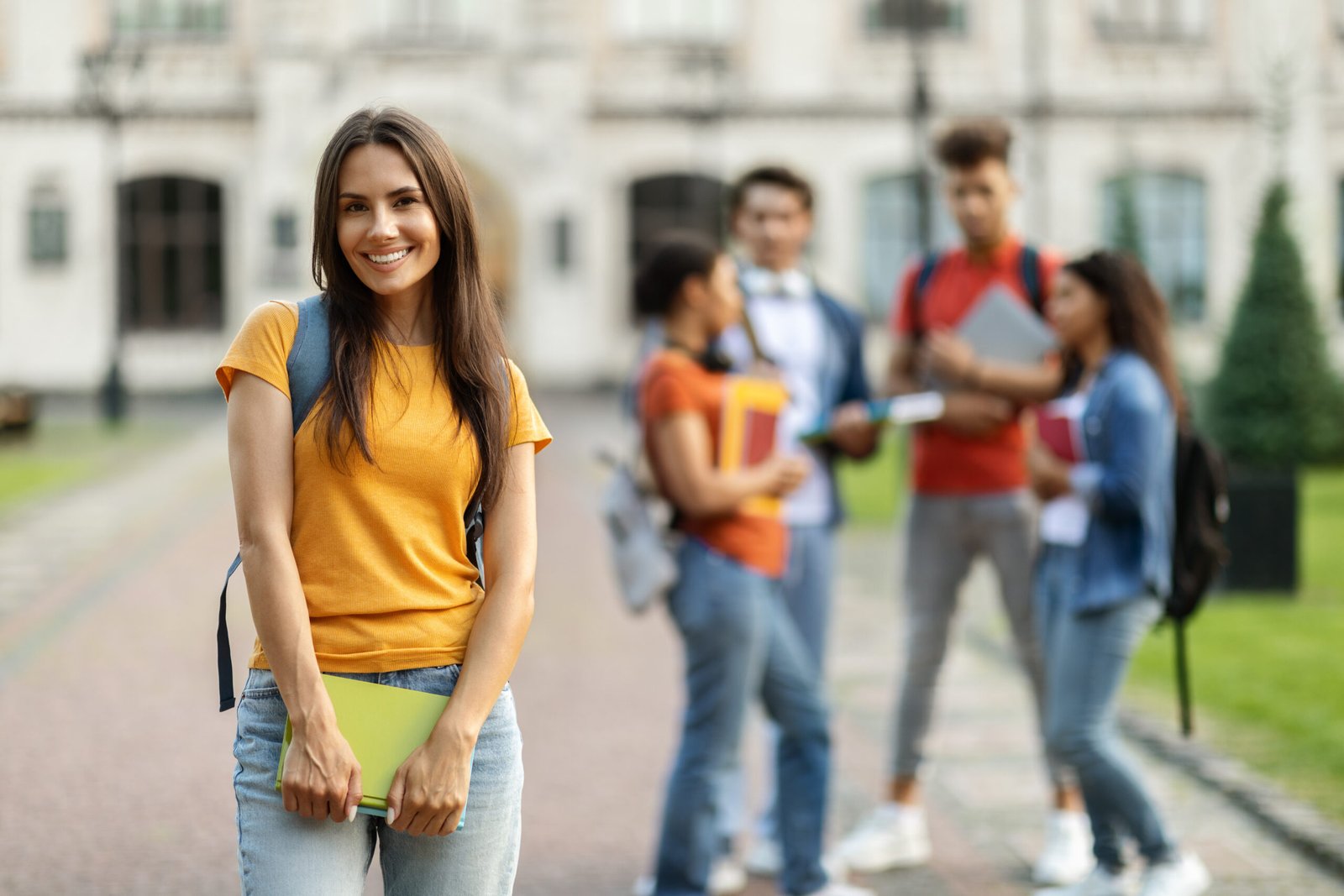 Student Life. Smiling young female posing in front college friends at campus